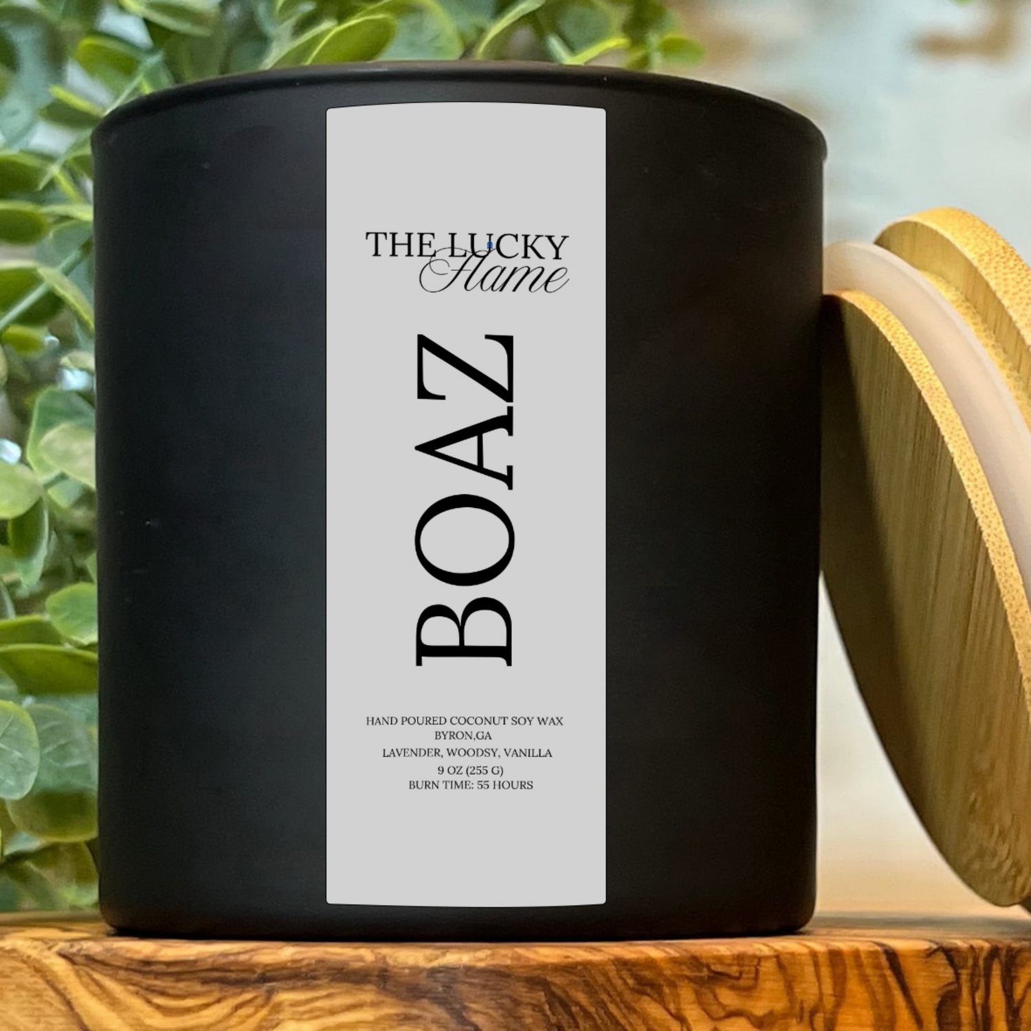 Boaz candle in a sleek 9 oz black jar with notes of lavender, vanilla, and woodsy undertones, styled with minimal, grounding decor and soft lighting.