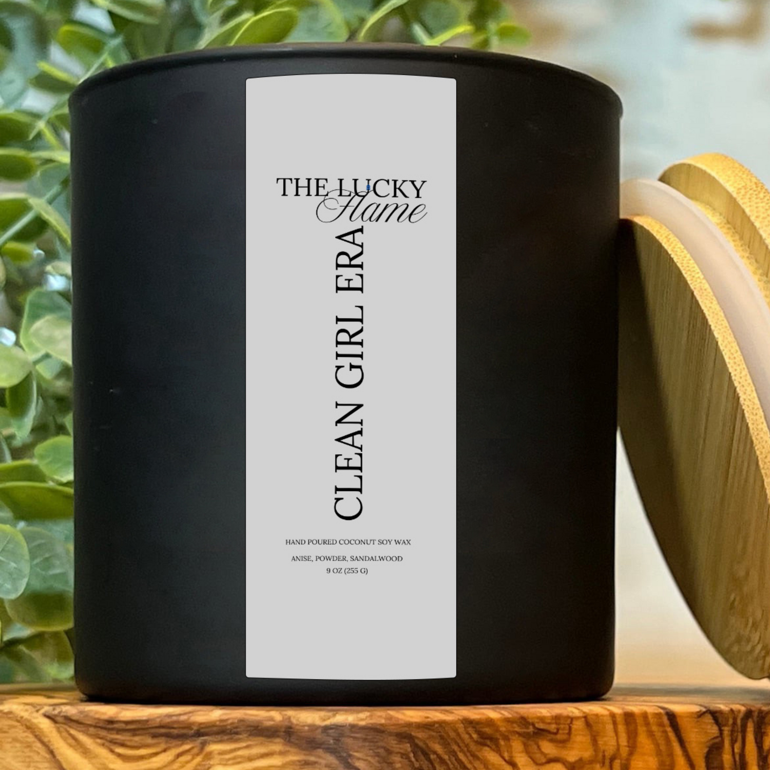 Clean Girl Era candle in a sleek 9 oz black jar with notes of anise, powder, and sandalwood, styled with minimal, fresh decor and soft white accents.