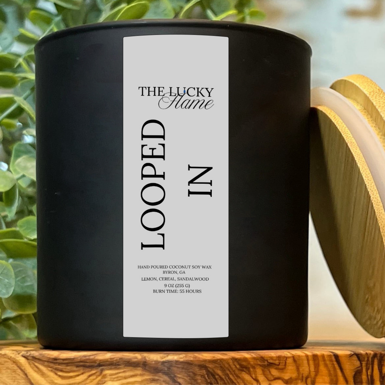 Looped In candle in a 9 oz black jar with fruity cereal, citrus, and vanilla notes, styled with colorful cereal pieces and playful, nostalgic props