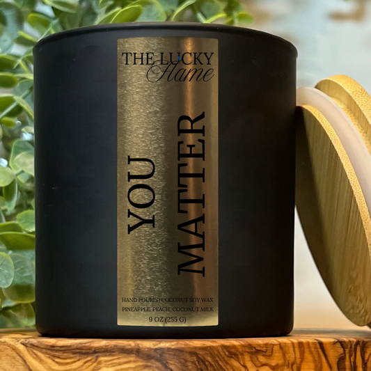 You Matter Candle by The Lucky Flame, featuring notes of orange peel, pineapple, peach, mango, sweet sugar, and creamy coconut milk in a 9 oz coconut soy blend.