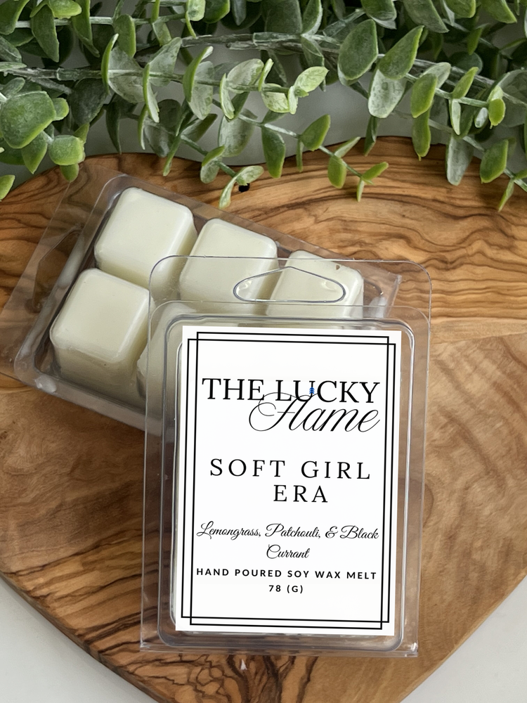 Candle wax melts in a clear container with a label on a wooden surface.